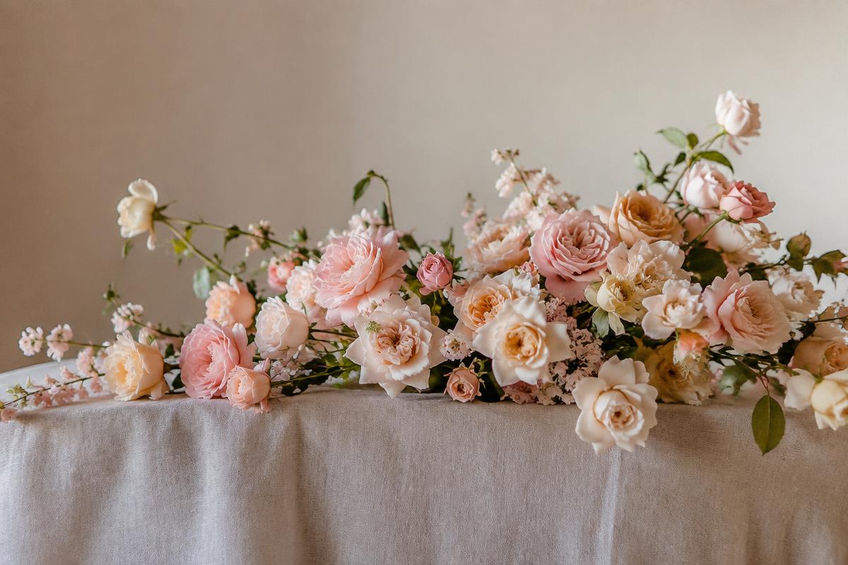 Blush, peach and cream silk roses across a linen table